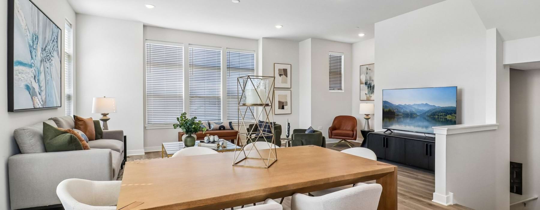 PARK5 Luxury Townhome dining room with wooden dining table and six white chairs with a living room in the background.