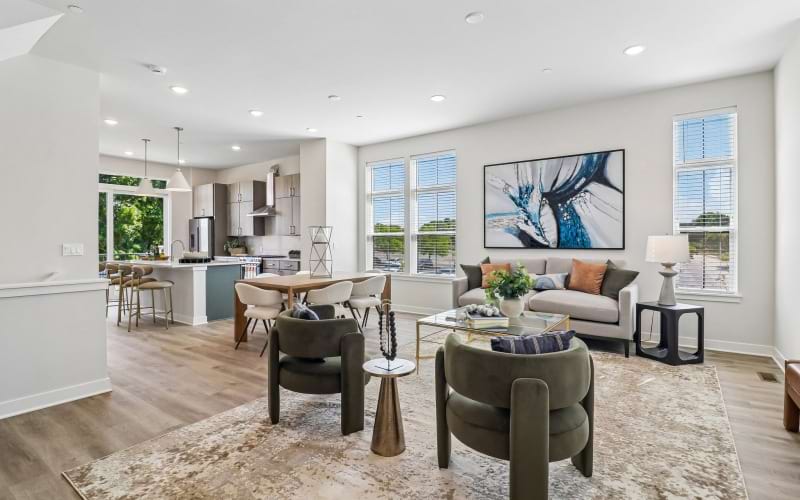 PARK5 Luxury Townhomes living room with green chairs, glass coffee table, grey couch and dining room/kitchen in the background.